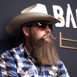 reklamná fotografia pre barbierstvo, muž v klobúku a slnečných okuliaroch s pestovanou bradou