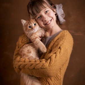 portrét dievčatka a jej oranžového mačiatka na hnedom pozadí