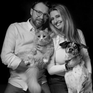 Muž a žena držiaci mačku a psa rodinný zvierací portrét v čiernobielej farbe